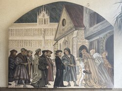 Eine Gruppe von Männern in historischer Kleidung unterhält sich und geht vor einer Kirche spazieren.