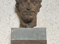 Eine verwitterte Büste von Philipp Melanchthon steht auf einem Sockel mit einer Gedenktafel, die sein Leben und seine Leistungen beschreibt.