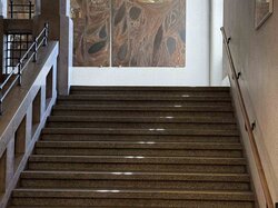 Treppenhaus mit gelben Streifen und Kunstwerken an der Wand.