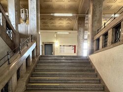 Treppe mit gelben Streifen, verschnörkelter Decke und Steinbalustrade.