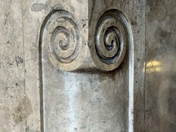 Nahaufnahme einer Marmoroberfläche mit zwei eingemeißelten Spiralmotiven.